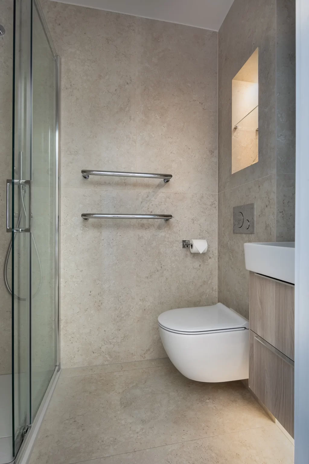 Compact ensuite bathroom with wall-hung toilet, vanity unit, and glass shower enclosure