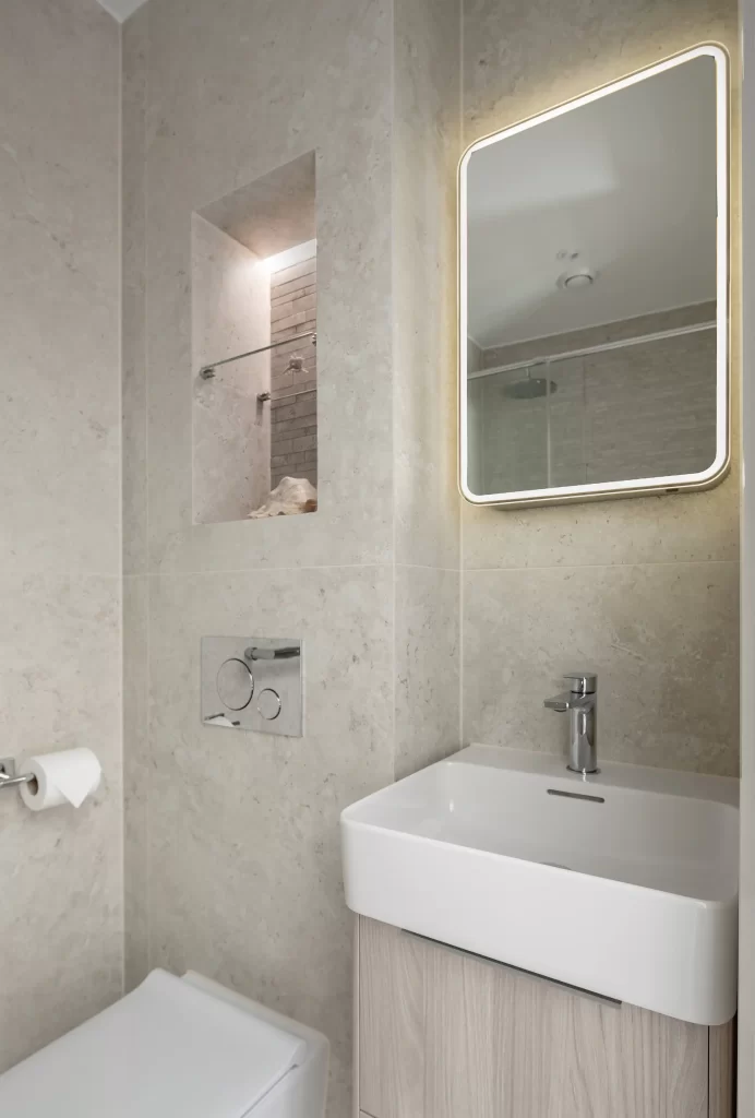 Bathroom vanity with illuminated mirror and stone-tiled wall