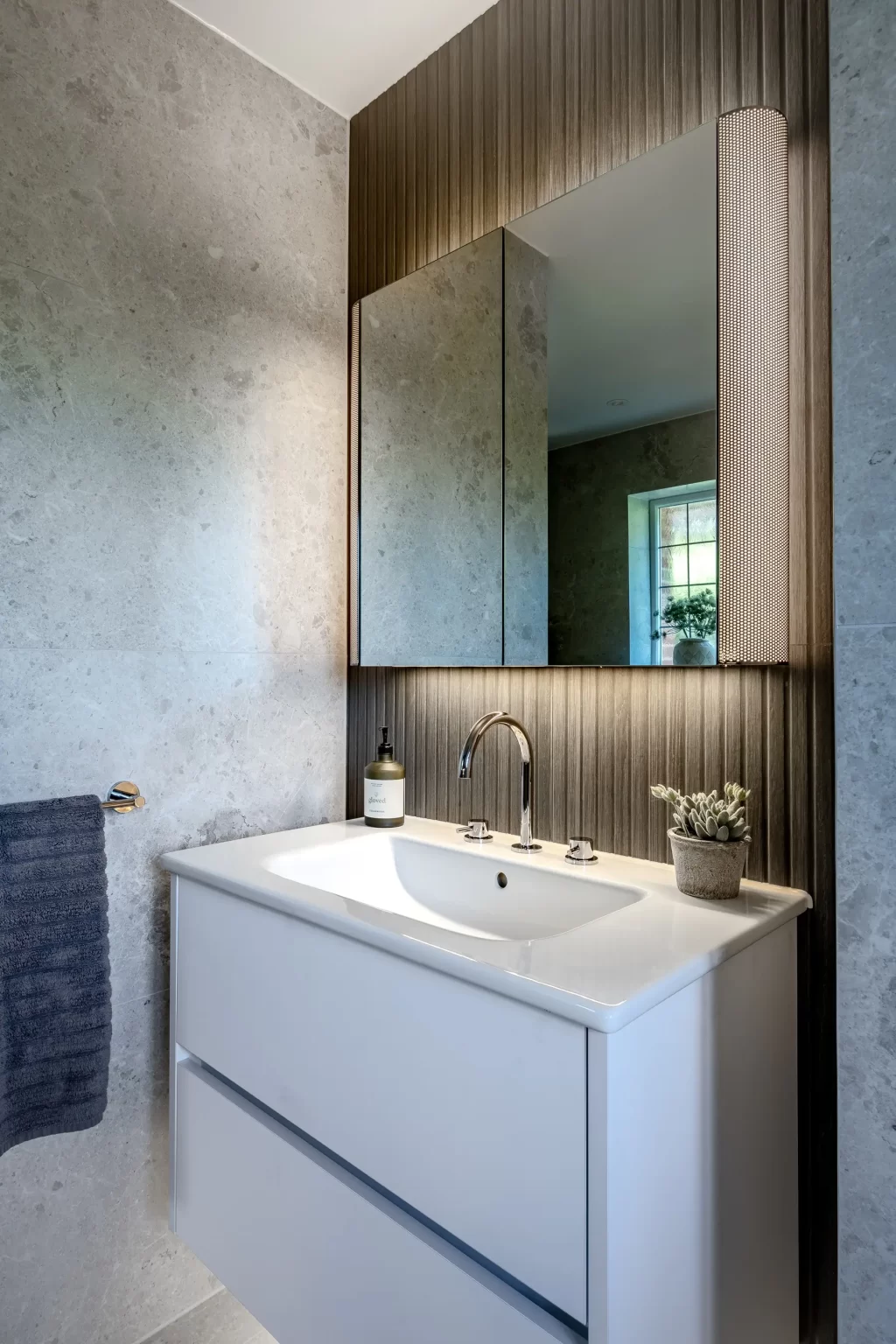 Modern vanity unit with illuminated mirror and grey textured wall