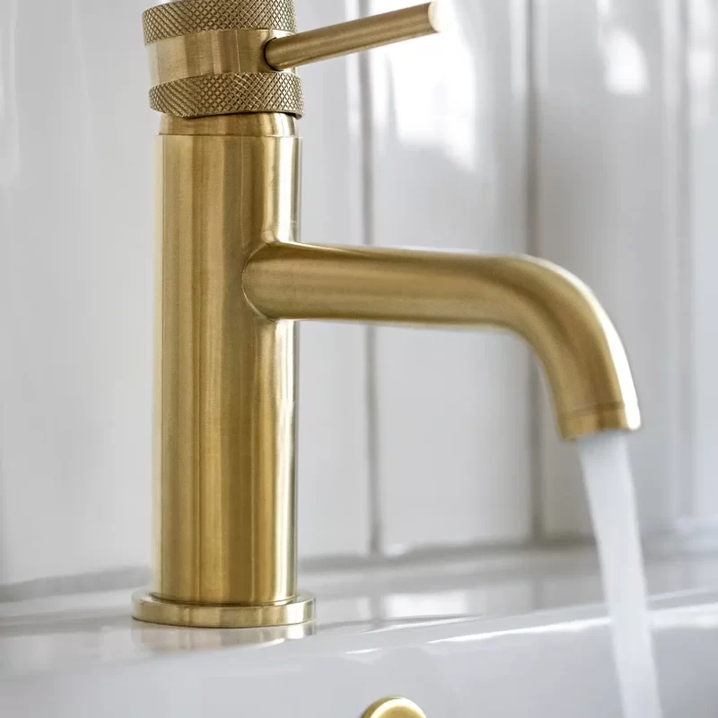 Close-up of brushed brass basin tap with running water