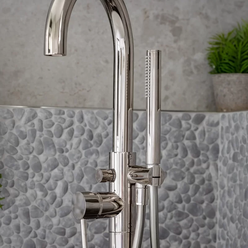 Chrome freestanding bath tap and hand shower against pebble wall