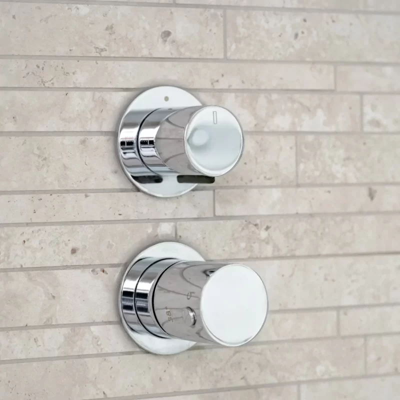 Close-up of chrome thermostatic shower controls on stone wall
