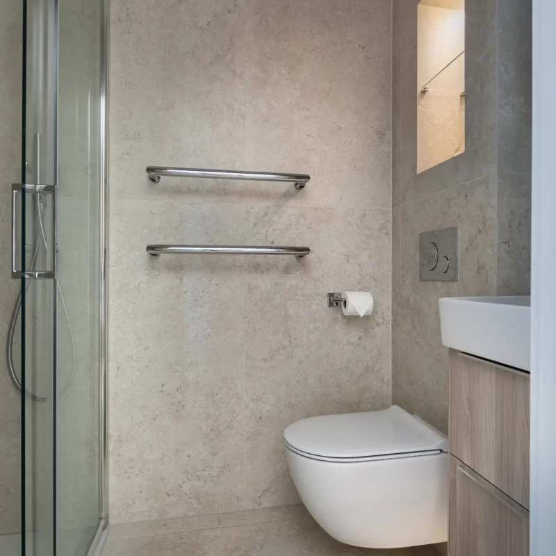 Compact ensuite bathroom with wall-hung toilet, vanity unit, and glass shower enclosure