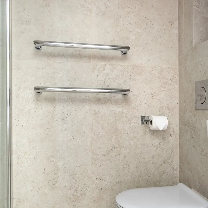 Ensuite bathroom with wall-hung toilet, chrome towel rails, and tiled walls