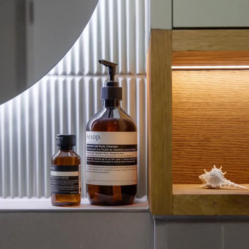 Detail of oak bathroom shelf with integrated LED lighting, bespoke renovation in Surrey with premium finishes.