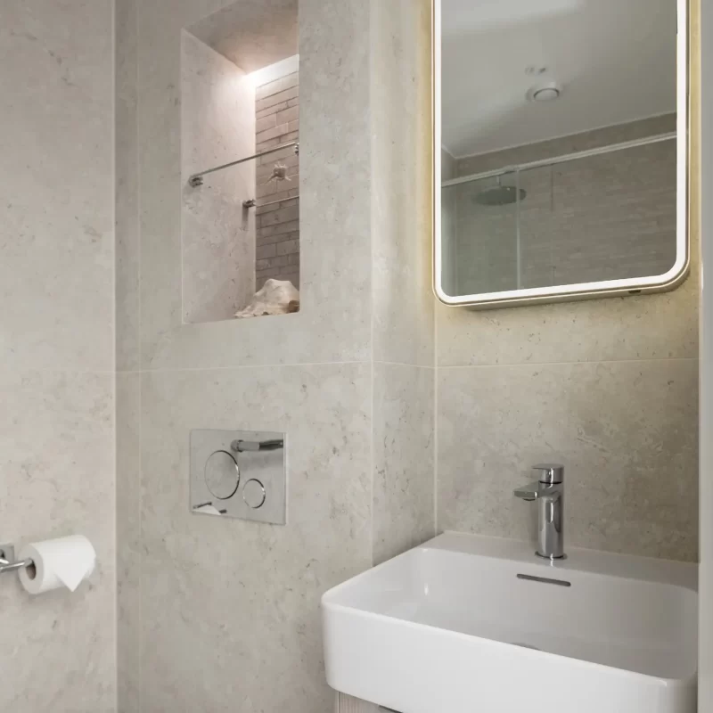Bathroom vanity with illuminated mirror and stone-tiled wall