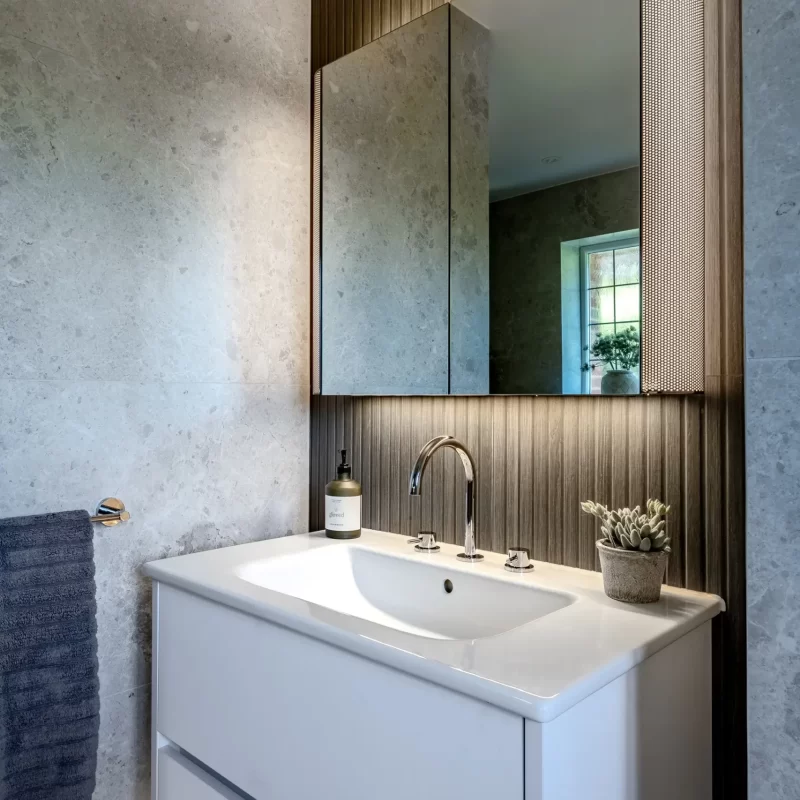 Modern vanity unit with illuminated mirror and grey textured wall