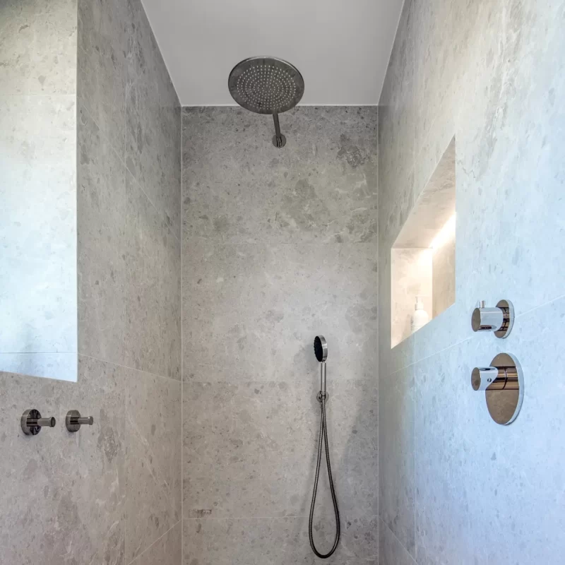 Walk-in shower with chrome rain shower and built-in niche, grey stone tiles