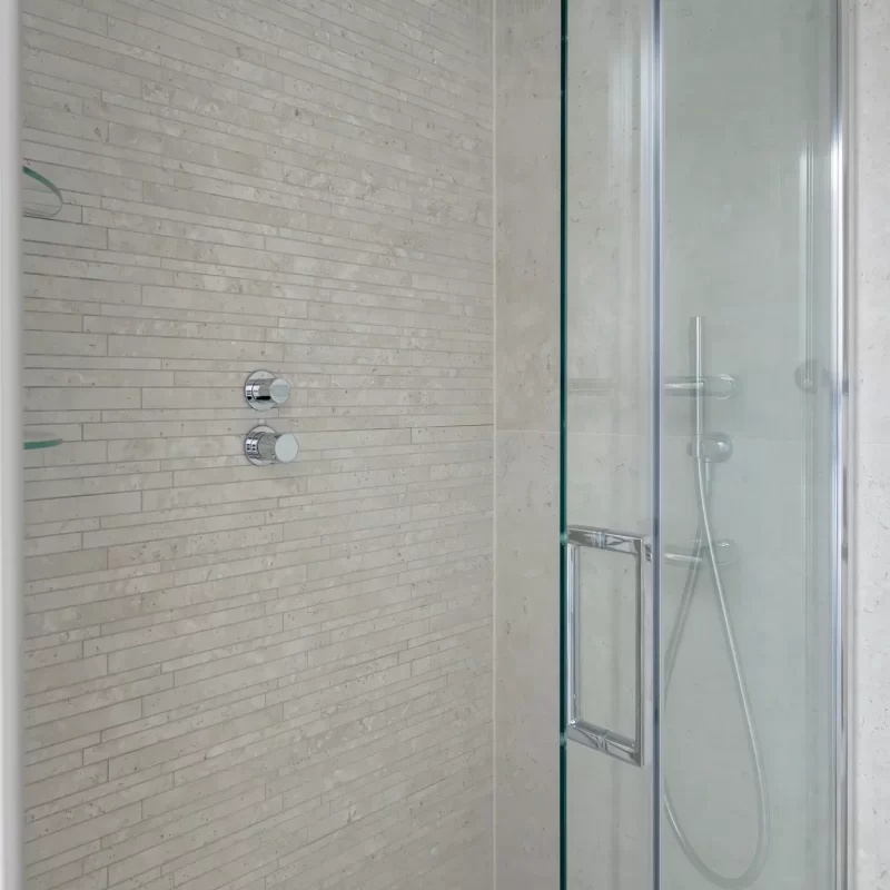 Walk-in shower with rainfall showerhead and stone-effect wall tiles